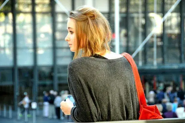 jeune femme profil regard sac rouge pull gris téléphone Capturer le Regard en Photographie : Mon Guide 2026