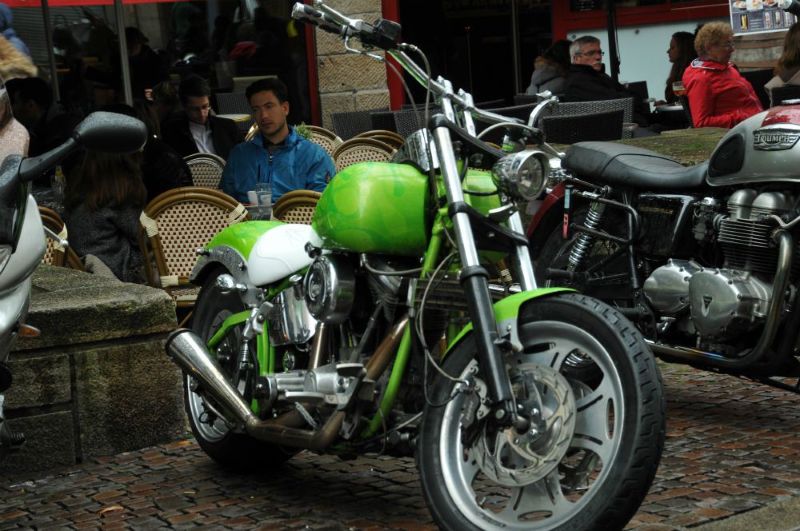 Motard en pause sur une route de l’Ouest français, illustrant un moment contemplatif pour l’Apéro Cosmique Motard stationné en bord de chaussée, lumière naturelle en fin de journée — photographie urbaine géolocalisée Ouest France