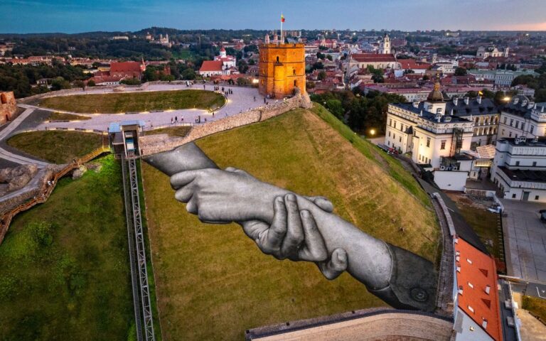 Saype peint la solidarité à Vilnius avec Beyond Walls, une fresque unique au pied de la tour de Gédiminas.