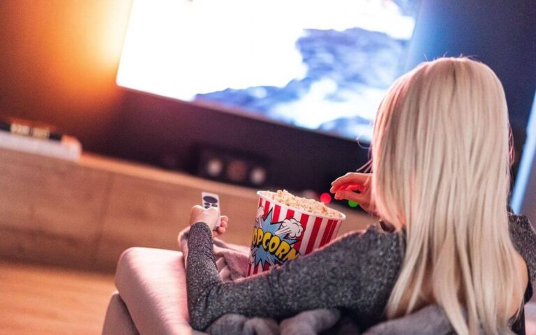 femme blonde regardant la télévision en mangeant du popcorn