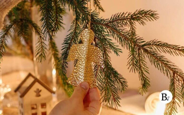 Mains qui accrochent un ange doré sur un sapin de Noël