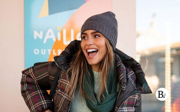 femme avec un grand sourire qui porte une doudoune écossaise et un bonnet
