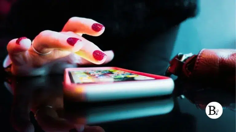 Femme avec un vernie à ongle rouge pianotant sur un iphone équipé d'une eSim
