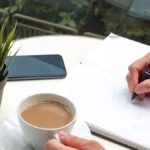personne qui écrit un article de blog avec un crayon en savourant un café
