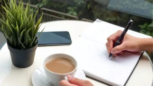 personne qui écrit un article de blog avec un crayon en savourant un café
