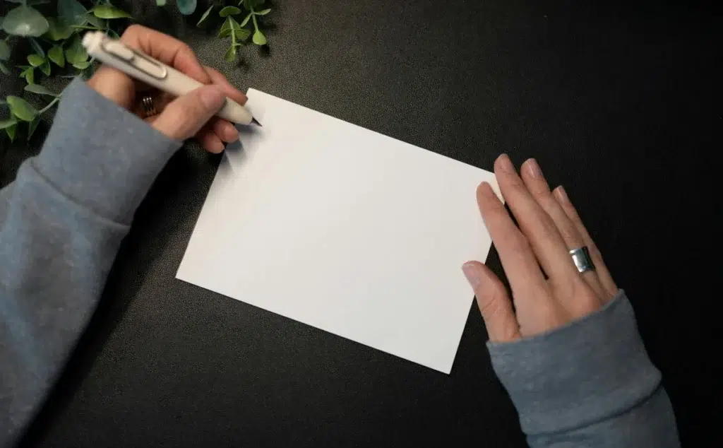 mains femme stylo feuille papier blanc Écrire avec l'IA sans perdre votre voix : la méthode