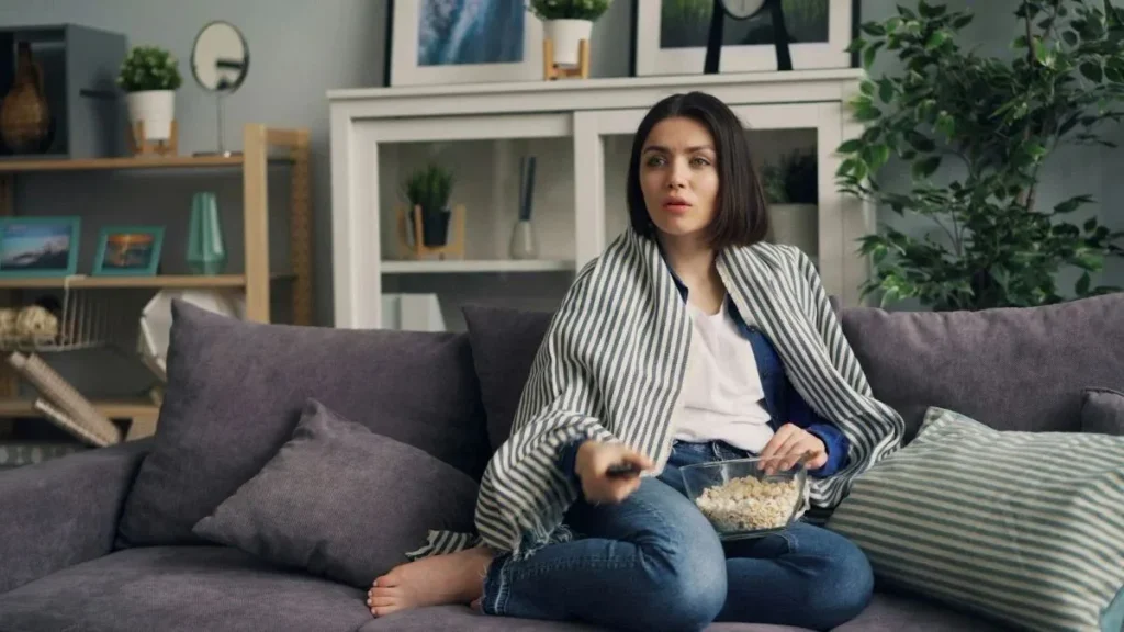 femme étonnée assise canapé télécommande smart tv Langues IPTV : vérifiez la VF et les sous-titres avant l’achat