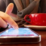 Main touchant l'écran d'un smartphone